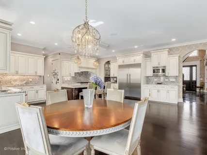 a kitchen with stainless steel appliances granite countertop a kitchen island a stove a table and chairs in it