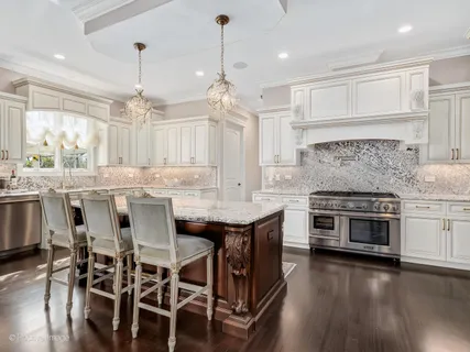 a kitchen with stainless steel appliances a stove a sink a center island and wooden floor