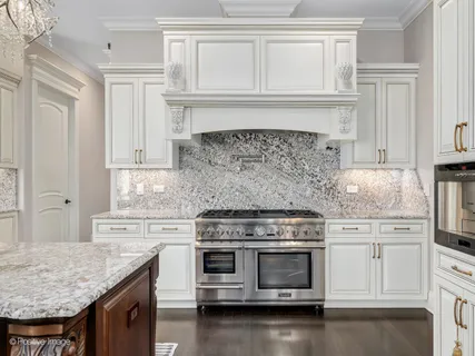 a kitchen with granite countertop a stove oven and white cabinets