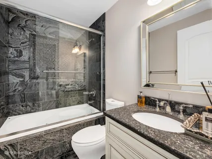 a bathroom with a granite countertop sink toilet mirror and bathtub