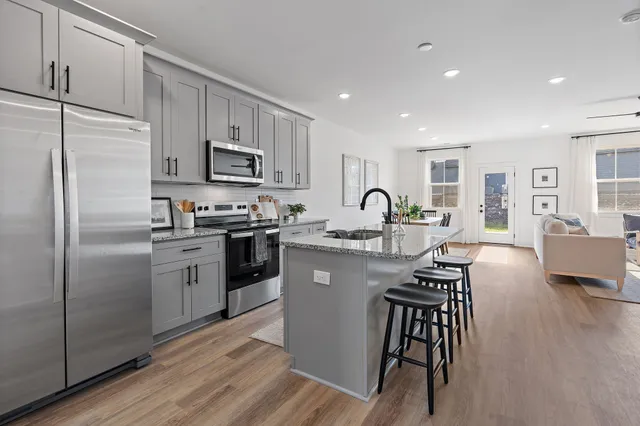 a kitchen with stainless steel appliances granite countertop a refrigerator a stove a sink dishwasher a stove with white cabinets and wooden floor