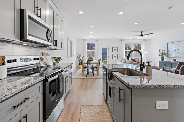 a kitchen with granite countertop stainless steel appliances a sink a stove top oven a counter space and cabinets