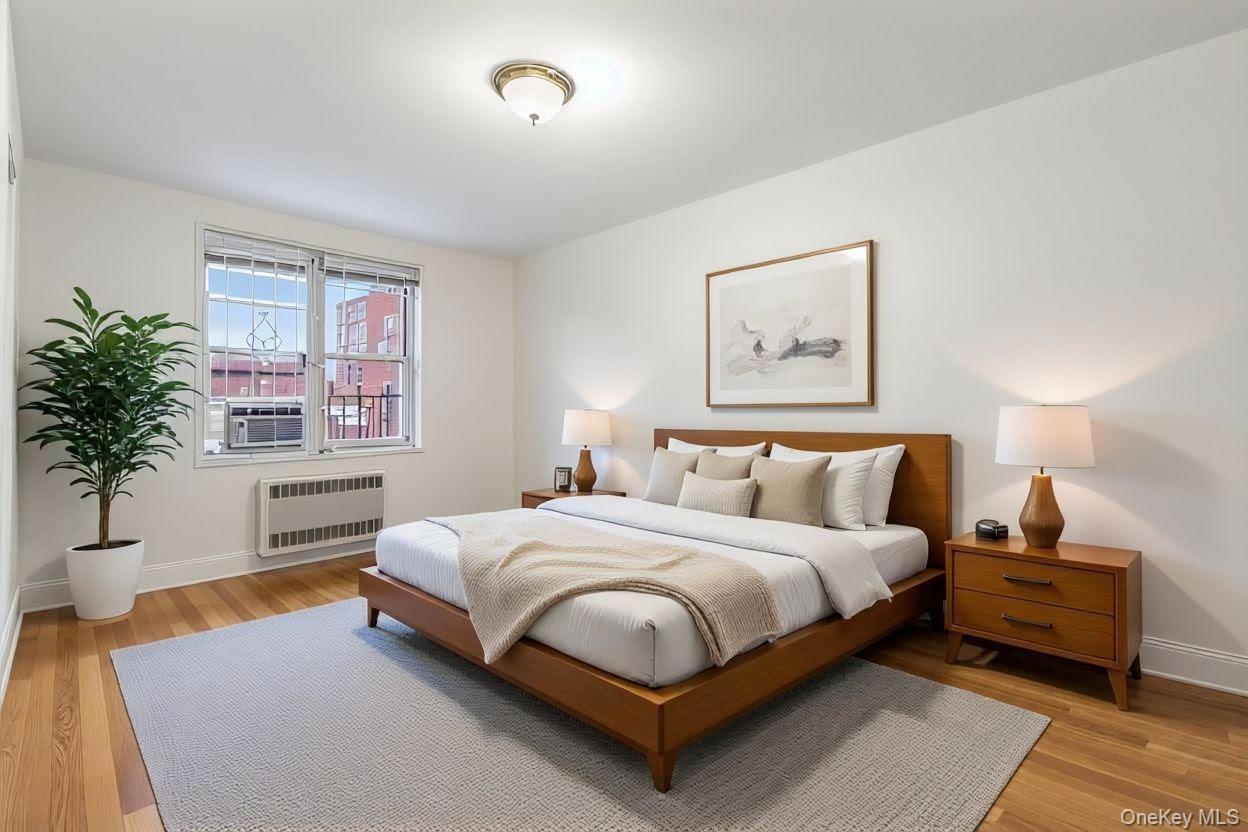 64-11 99th Street, Unit 3O4 Queens, NY 11374 - Photo 16 of 23 Bedroom featuring light wood finished floors, radiator heating unit, and cooling unit