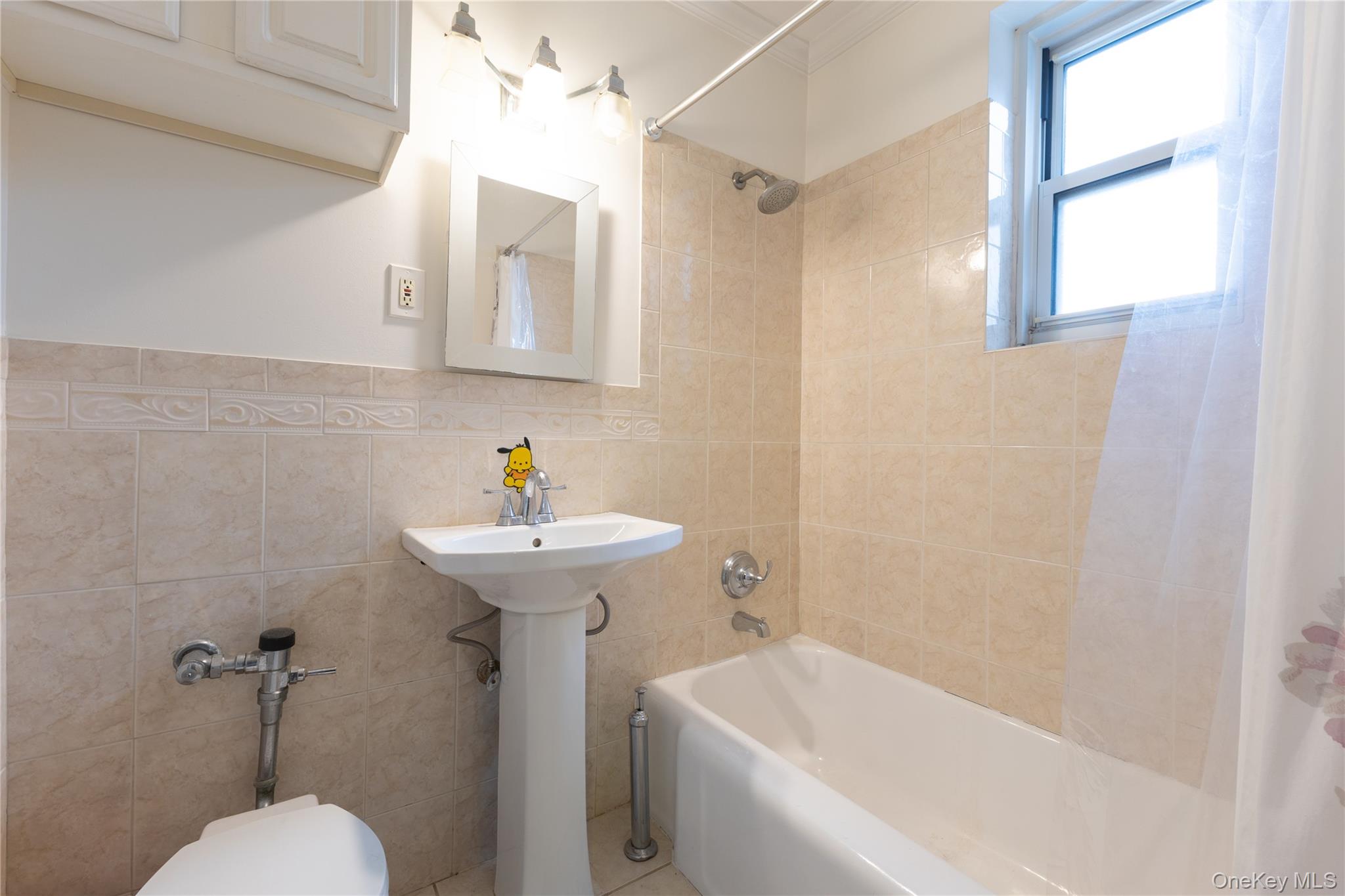 64-11 99th Street, Unit 3O4 Queens, NY 11374 - Photo 19 of 23 Bathroom featuring shower / bath combo with shower curtain and tile walls