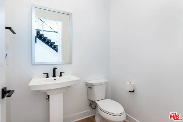 a view of empty room with wooden floor and kitchen
