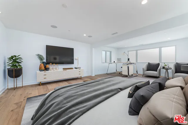 a spacious bedroom with a bed and wooden floor