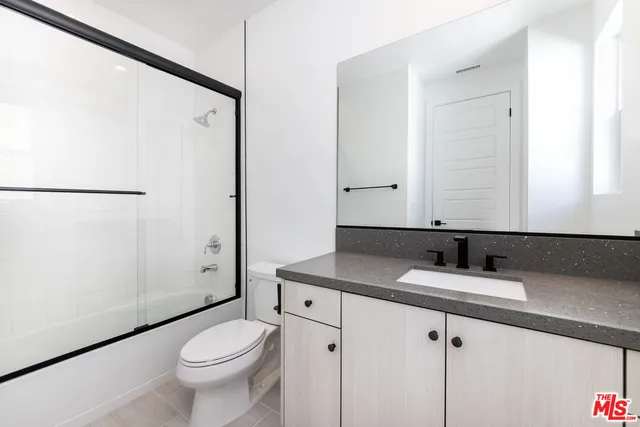 a bathroom with a granite countertop sink toilet and shower
