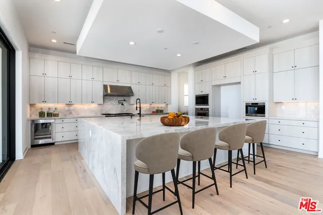 a kitchen with granite countertop a refrigerator oven a sink dishwasher and white cabinets with wooden floor