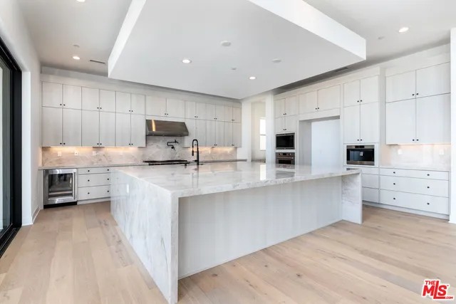 a large kitchen with stainless steel appliances kitchen island a large counter top and view of living room