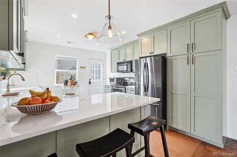 a kitchen with stainless steel appliances granite countertop a refrigerator a sink dishwasher a stove and a dining table with wooden floor
