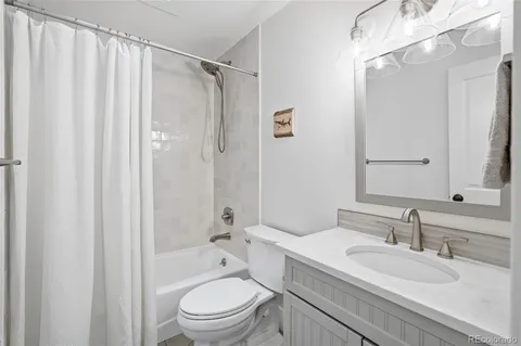 a bathroom with a granite countertop sink a toilet and shower