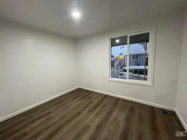 a view of an empty room with a window and a kitchen