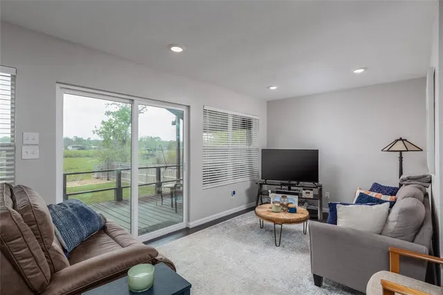 a living room with furniture a flat screen tv and a floor to ceiling window