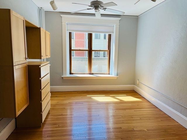 a view of an empty room with a window and wooden floor