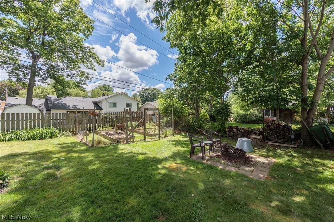 5364 Summit Road Lyndhurst, OH 44124 - Photo 41 of 42 Expansive backyard featuring a lush lawn, mature trees, a fire pit area with paver stones, and a raised garden bed