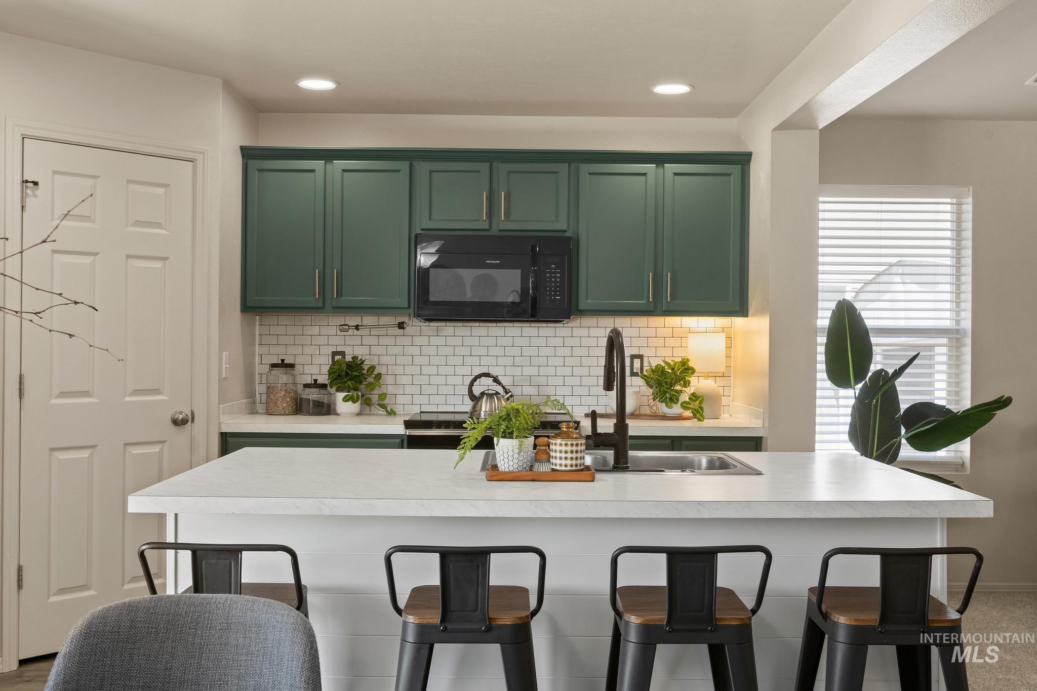 5506 Barkley Way Caldwell, ID 83607 - Photo 12 of 34 Kitchen featuring deep green cabinetry, white subway tile backsplash, and light-toned countertops