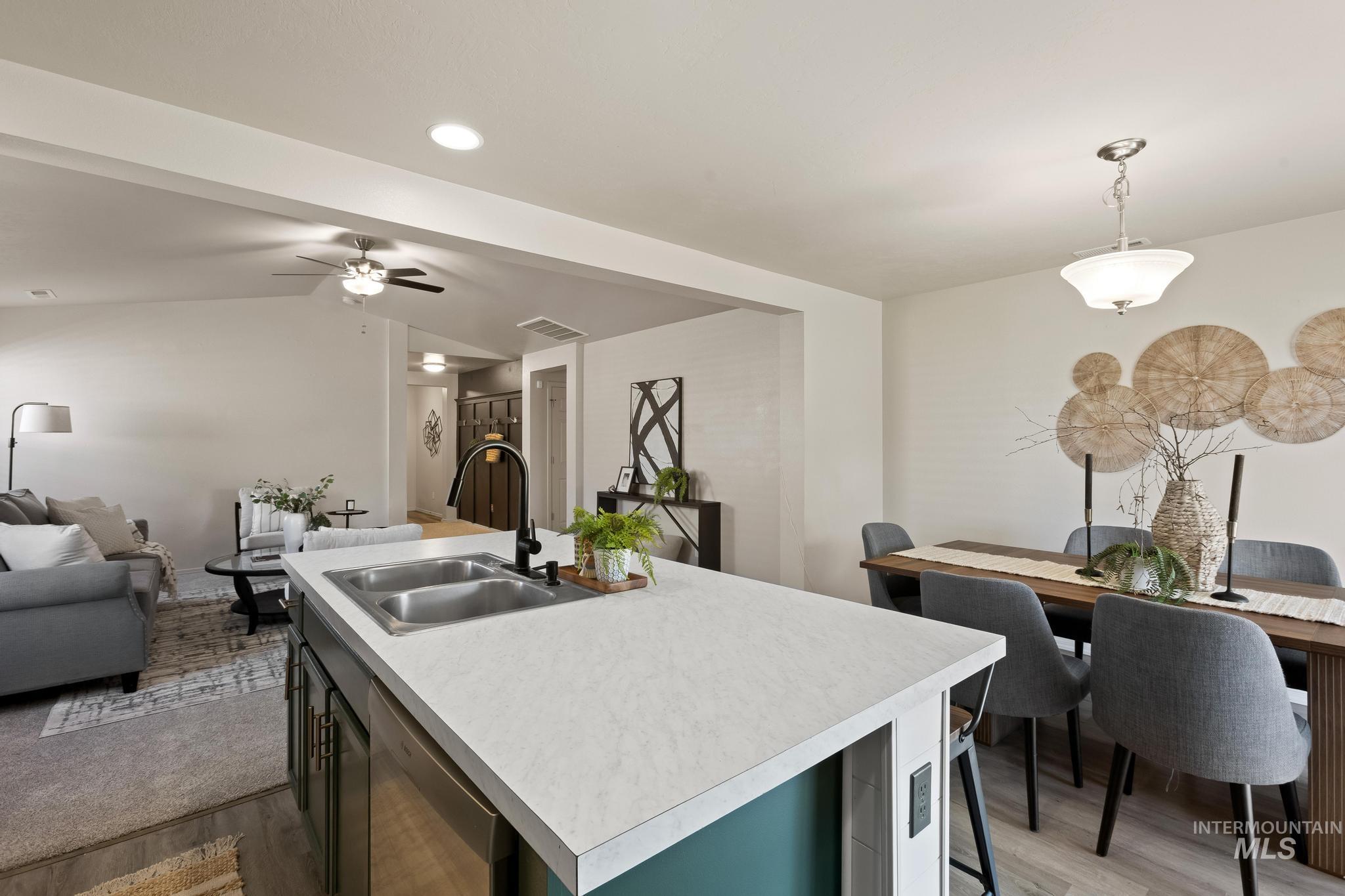 5506 Barkley Way Caldwell, ID 83607 - Photo 14 of 34 Kitchen island with a dual basin stainless steel sink, black faucet, and light-toned countertop
