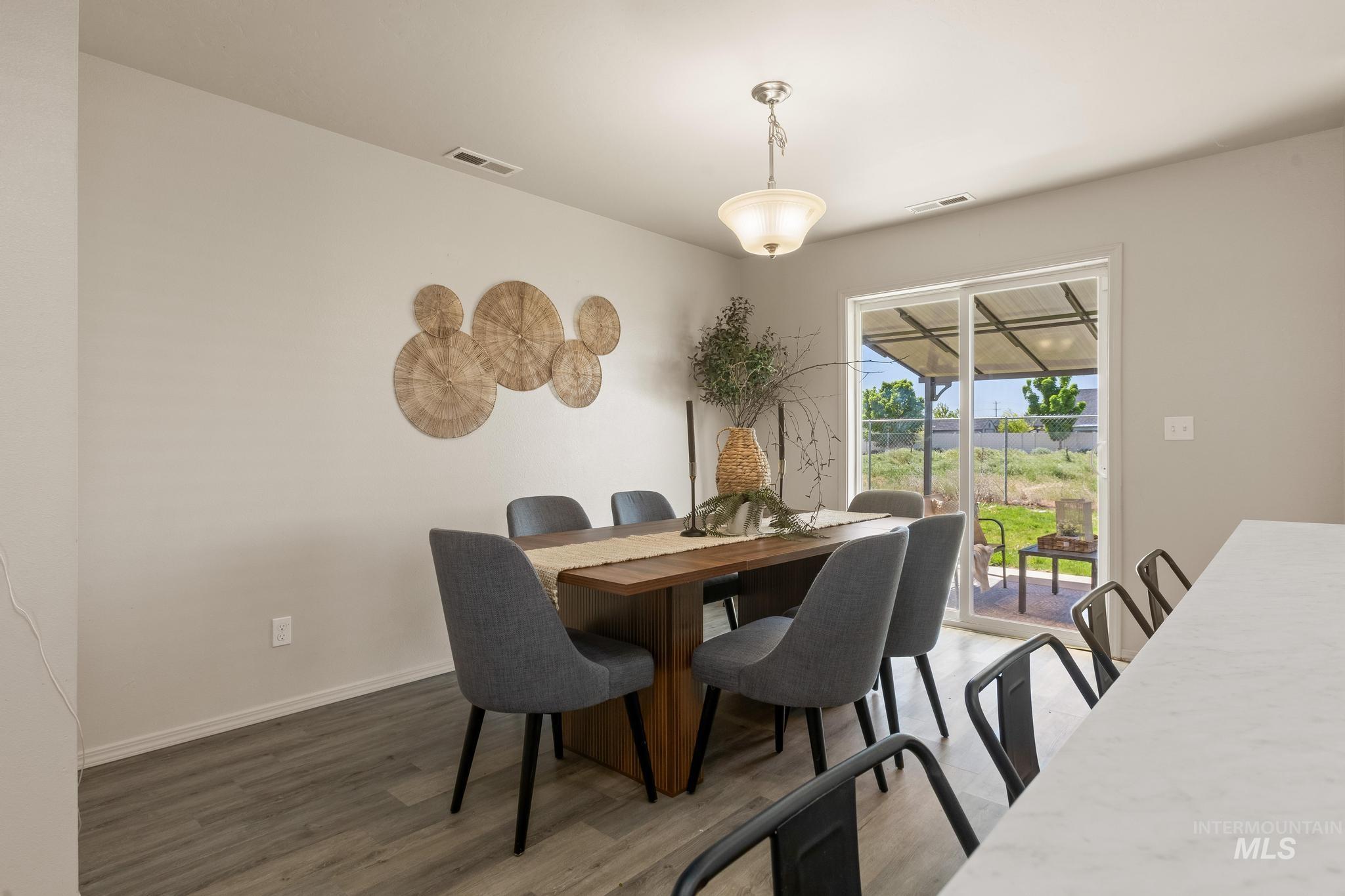 5506 Barkley Way Caldwell, ID 83607 - Photo 16 of 34 Dining area featuring wood-finish flooring, a contemporary ceiling light fixture, and sliding glass doors to the exterior