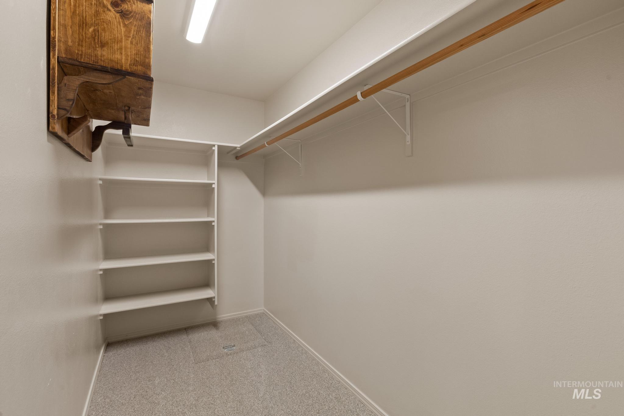 5506 Barkley Way Caldwell, ID 83607 - Photo 25 of 34 Walk-in closet featuring white built-in shelving, a wood-finish hanging rod, light gray carpet, and overhead strip lighting