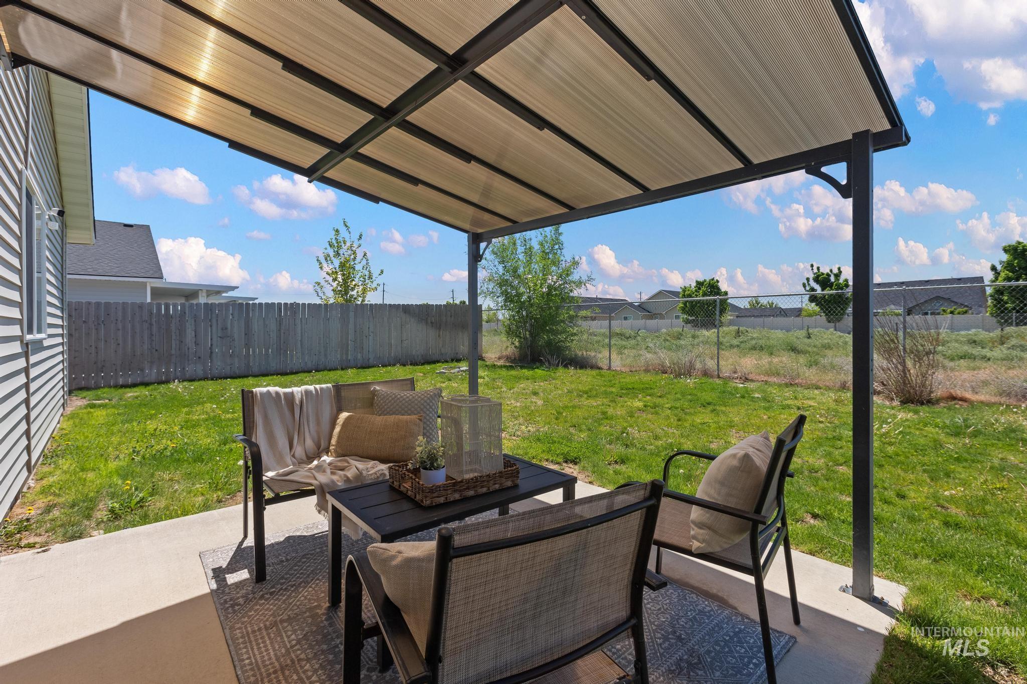 5506 Barkley Way Caldwell, ID 83607 - Photo 34 of 34 Covered patio area featuring a metal frame pergola with a translucent roof, concrete patio slab, and a green grass yard