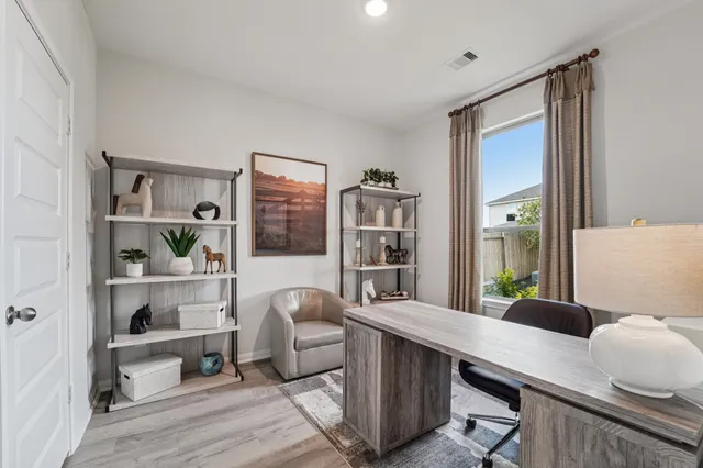 a room with a desk chairs and book shelf