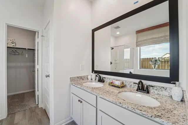 a bathroom with a granite countertop double vanity sink and a mirror