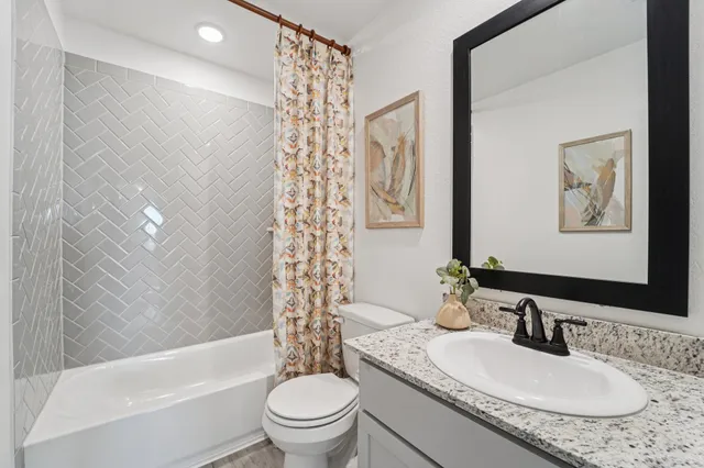 a bathroom with a granite countertop sink toilet and a bathtub