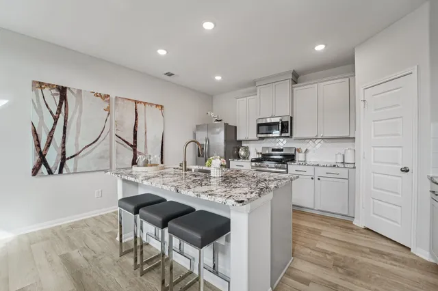 a kitchen with kitchen island granite countertop a sink cabinets and wooden floor