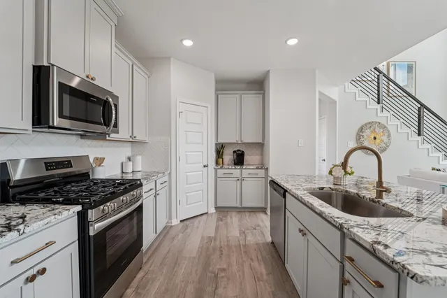 a kitchen with granite countertop a sink stainless steel appliances and cabinets
