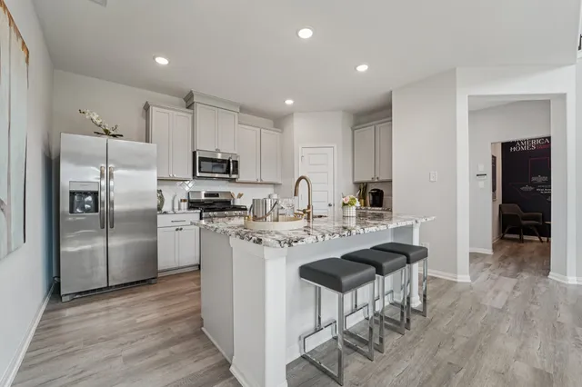 a kitchen with refrigerator and chairs