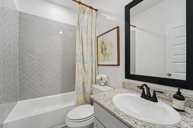 a bathroom with a granite countertop sink toilet tub and shower
