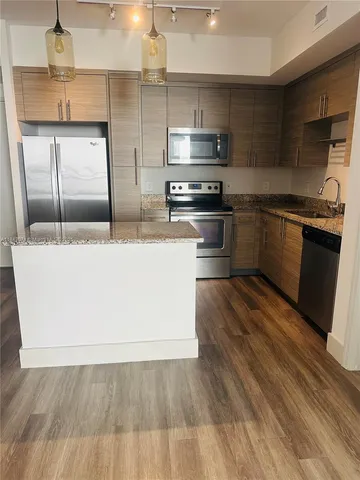 a kitchen with stainless steel appliances granite countertop a sink a stove and a refrigerator