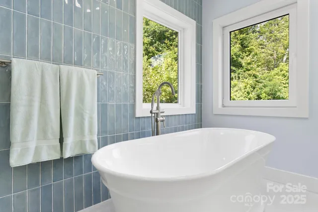 a white bath tub sitting in a bathroom next to a window