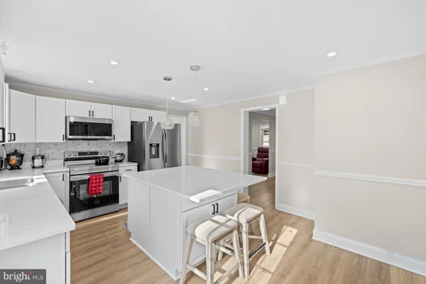 a kitchen with granite countertop a refrigerator a sink a stove a dining table and chairs