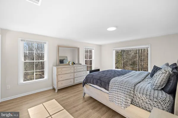 a spacious bedroom with a bed and wooden floor