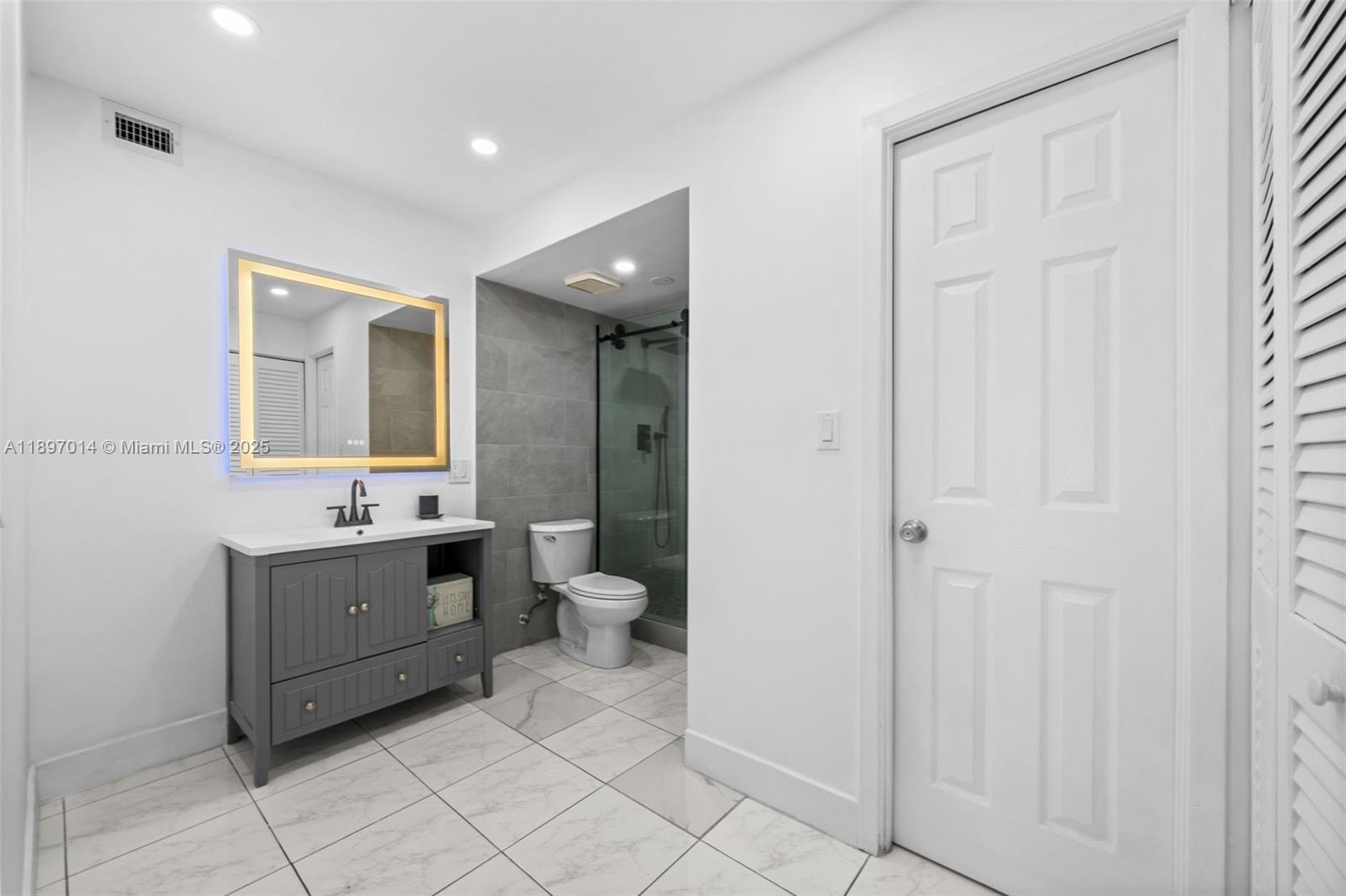 401 Golden Isles Drive, Unit 304 Hallandale Beach, FL 33009 - Photo 12 of 43 a bathroom with a sink a toilet and mirror