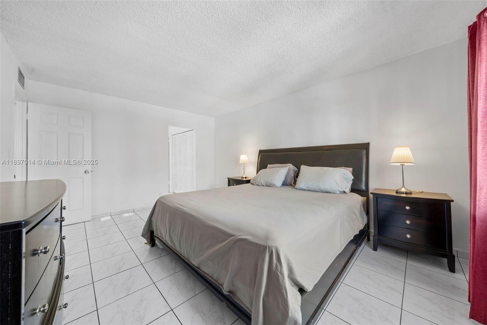 401 Golden Isles Drive, Unit 304 Hallandale Beach, FL 33009 - Photo 17 of 43 a bedroom with a bed and a lamp