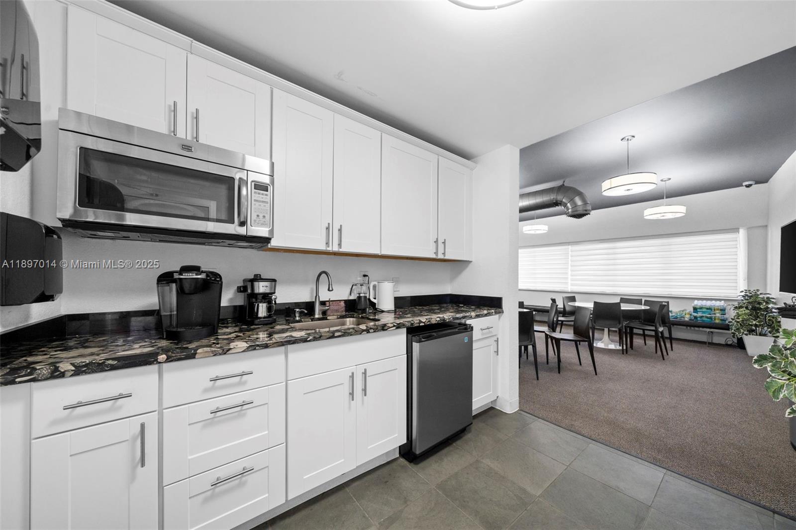 401 Golden Isles Drive, Unit 304 Hallandale Beach, FL 33009 - Photo 31 of 43 a kitchen with stainless steel appliances granite countertop a stove a sink and a microwave