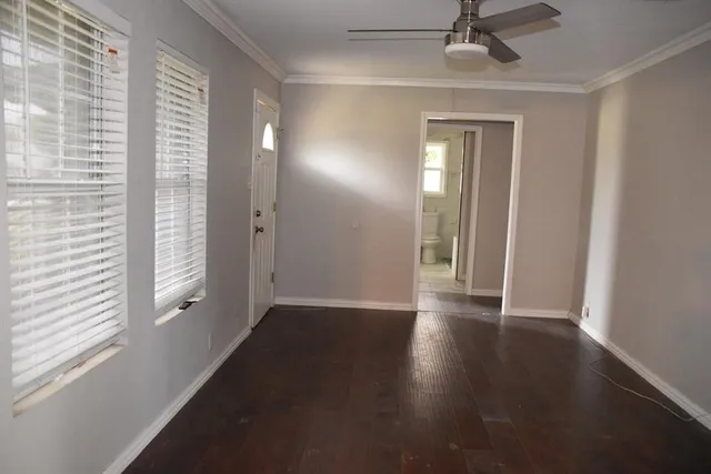 a view of an empty room with a window and wooden floor