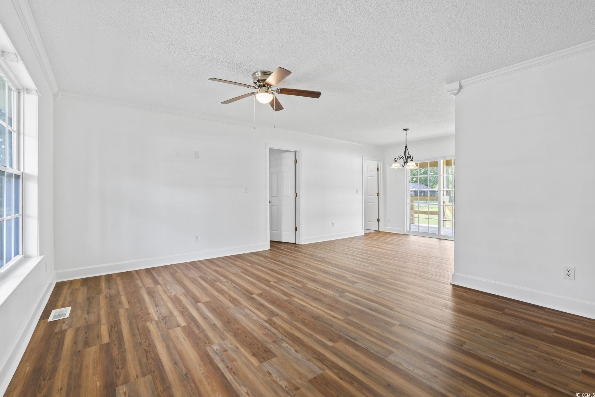 568 Rosedale Drive Aynor, SC 29511 - Photo 5 of 38 Spare room featuring dark wood-type flooring, a chandelier, a textured ceiling, a ceiling fan, and crown molding