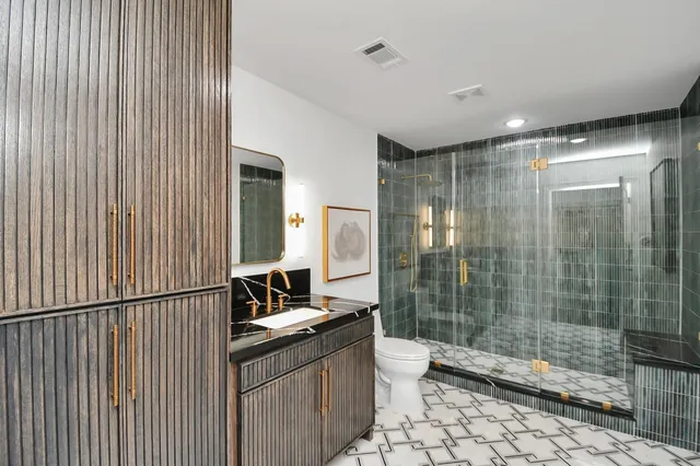 a bathroom with a double vanity sink toilet and shower