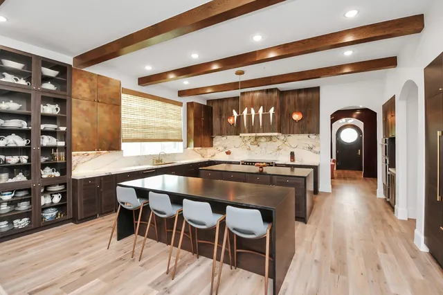 a dining hall with stainless steel appliances kitchen island a table and chairs in it