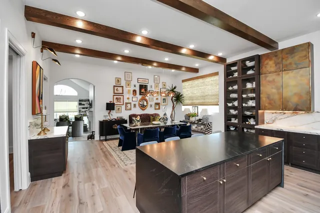 a large living room with stainless steel appliances kitchen island granite countertop a table chairs in it and wooden floors