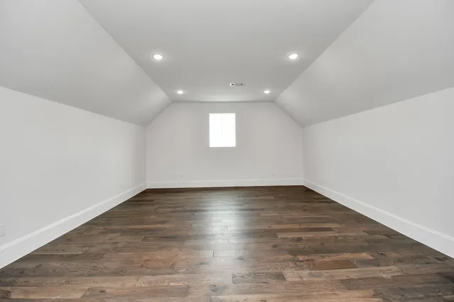 a view of an empty room with wooden floor and window