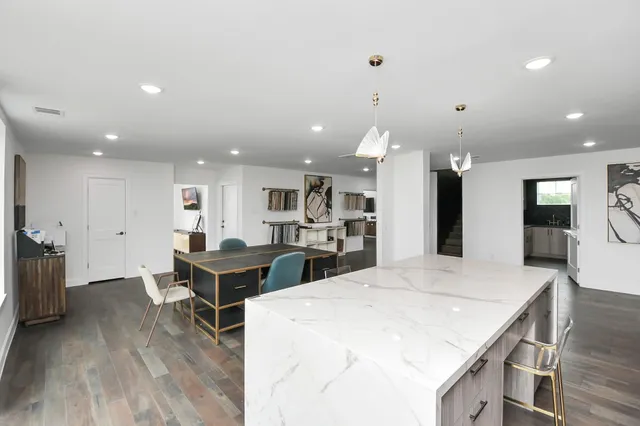 a large kitchen with kitchen island a stove a refrigerator a sink a dining table and chairs with wooden floor