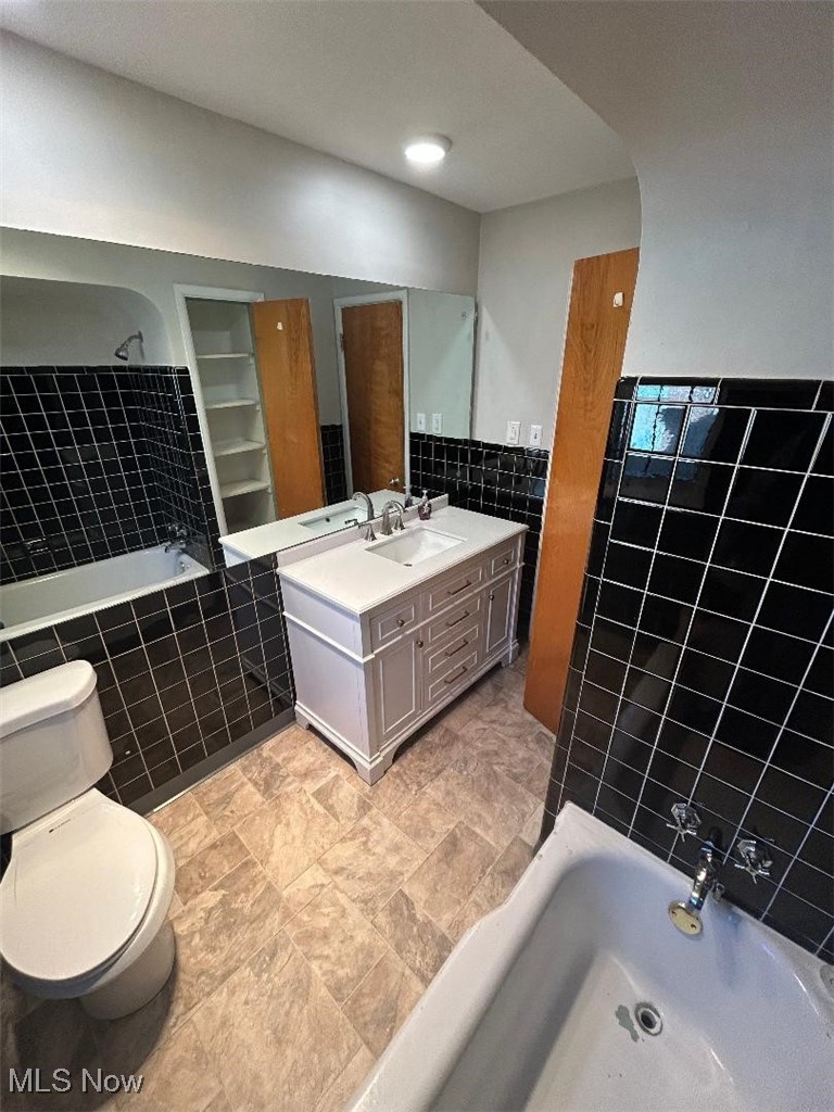 1130 Carver Road Cleveland, OH 44112 - Photo 13 of 32 Full bathroom featuring tub / shower combination, vanity, toilet, and tile walls