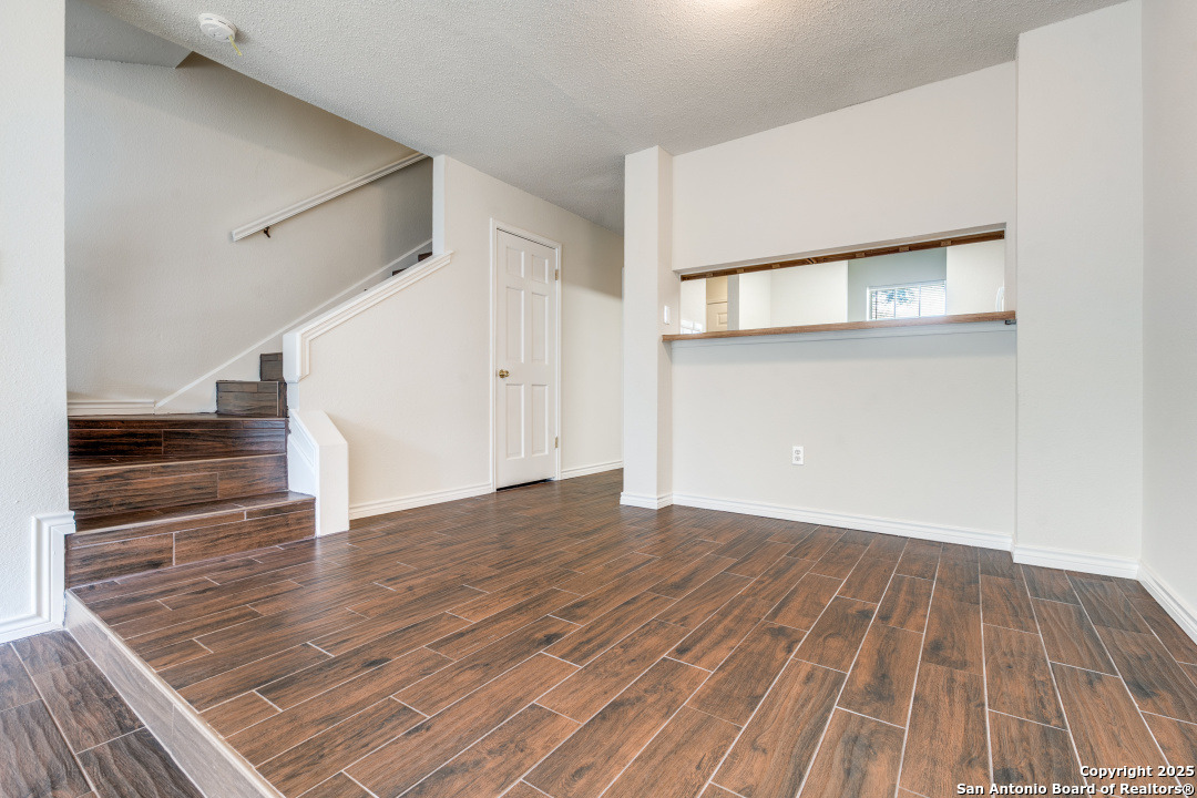 10254 Dover Ridge, Unit 204 San Antonio, TX 78250 - Photo 13 of 31 a view of an empty room with wooden floor and stairs
