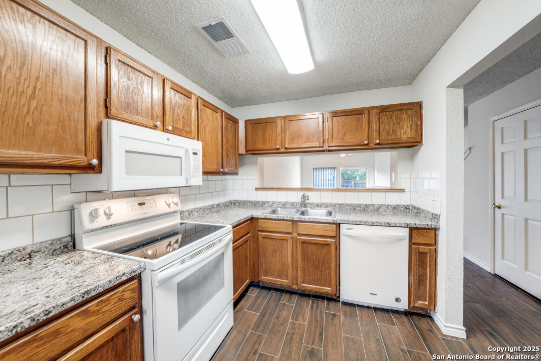 10254 Dover Ridge, Unit 204 San Antonio, TX 78250 - Photo 16 of 31 a kitchen with a sink stove and cabinets
