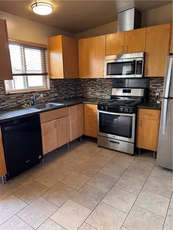 a kitchen with stainless steel appliances granite countertop a stove a sink dishwasher and a refrigerator