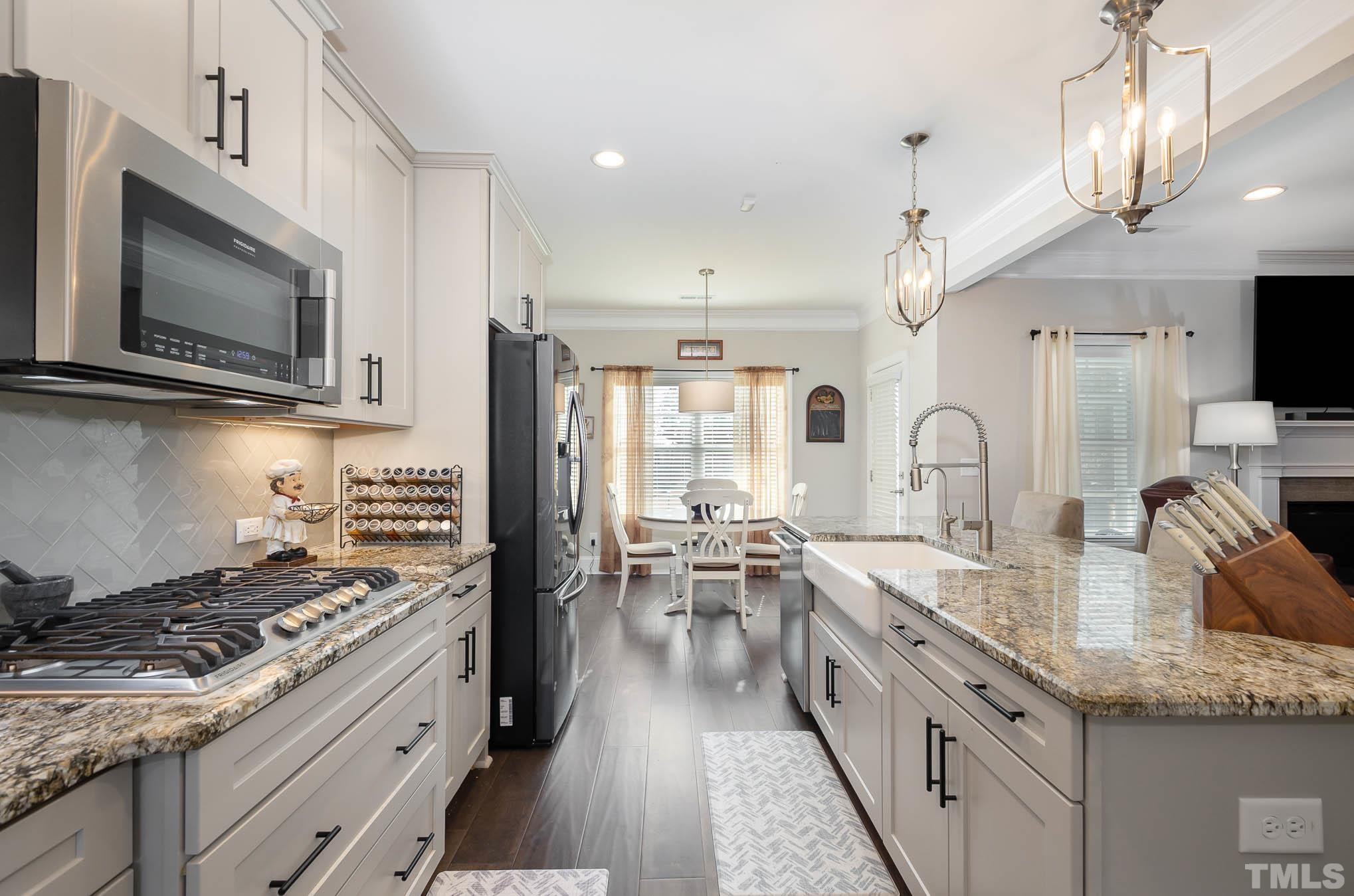 8801 Rainer Way Wake Forest, NC 27587 - Photo 11 of 34 a kitchen with stainless steel appliances kitchen island granite countertop a stove top oven a sink dishwasher a dining table and chairs with wooden floor